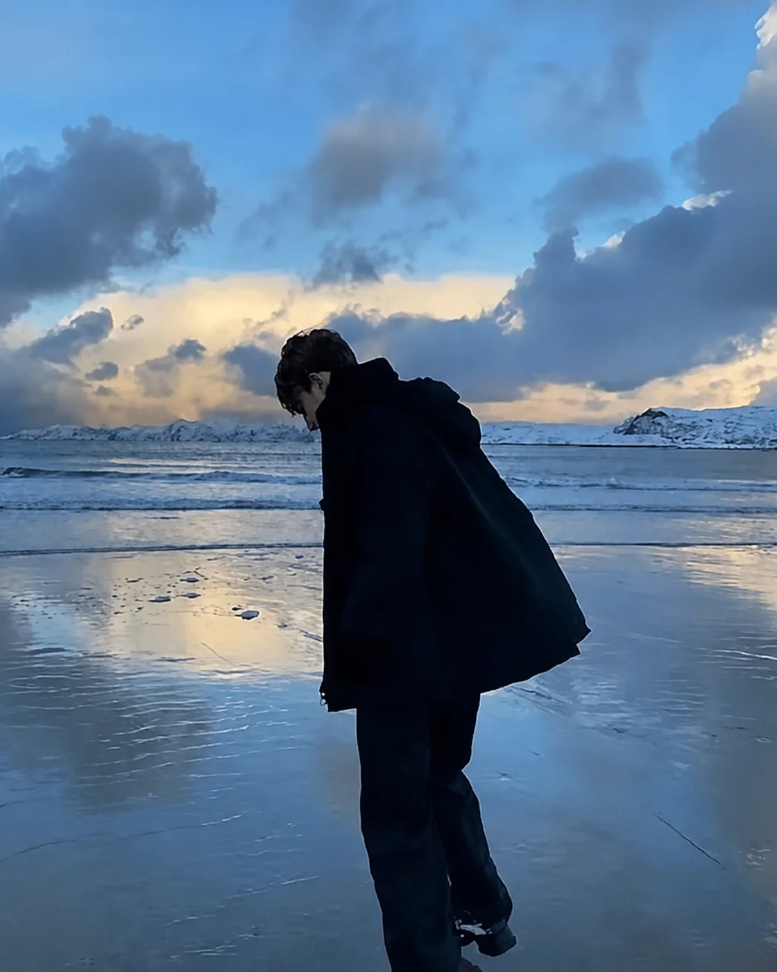 海边冰滩上低头前行的少年身影